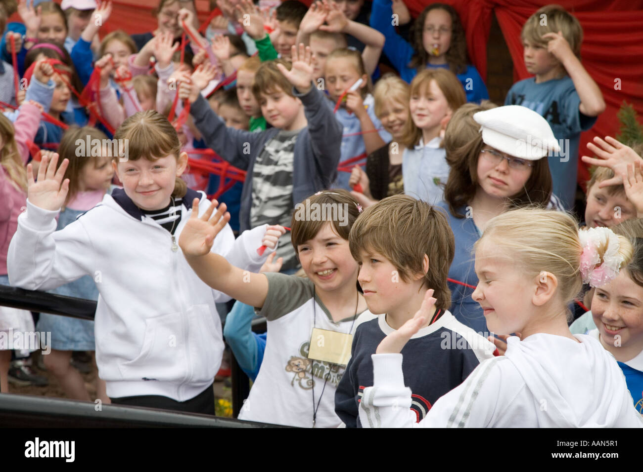 Gruppe von Kindern, die bei der öffentlichen Eröffnung einer neuen Dorfhalle Wales UK winken lachend Stockfoto