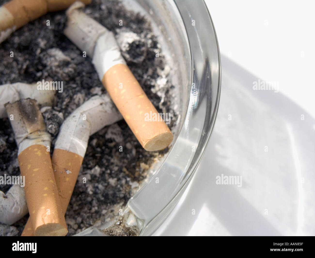 EIN GLAS ASCHENBECHER VOLLER ASCHE UND ZIGARETTENKIPPEN ENDEN Stockfoto