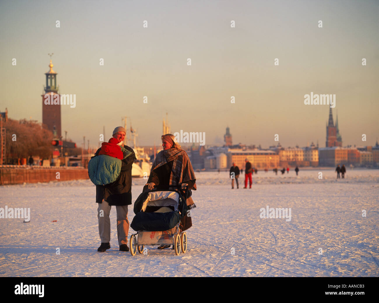 Familie schieben Kinderwagen über gefrorene Riddarfjarden in Stockholm Winter mit Rathaus oder Stadthaus links Stockfoto