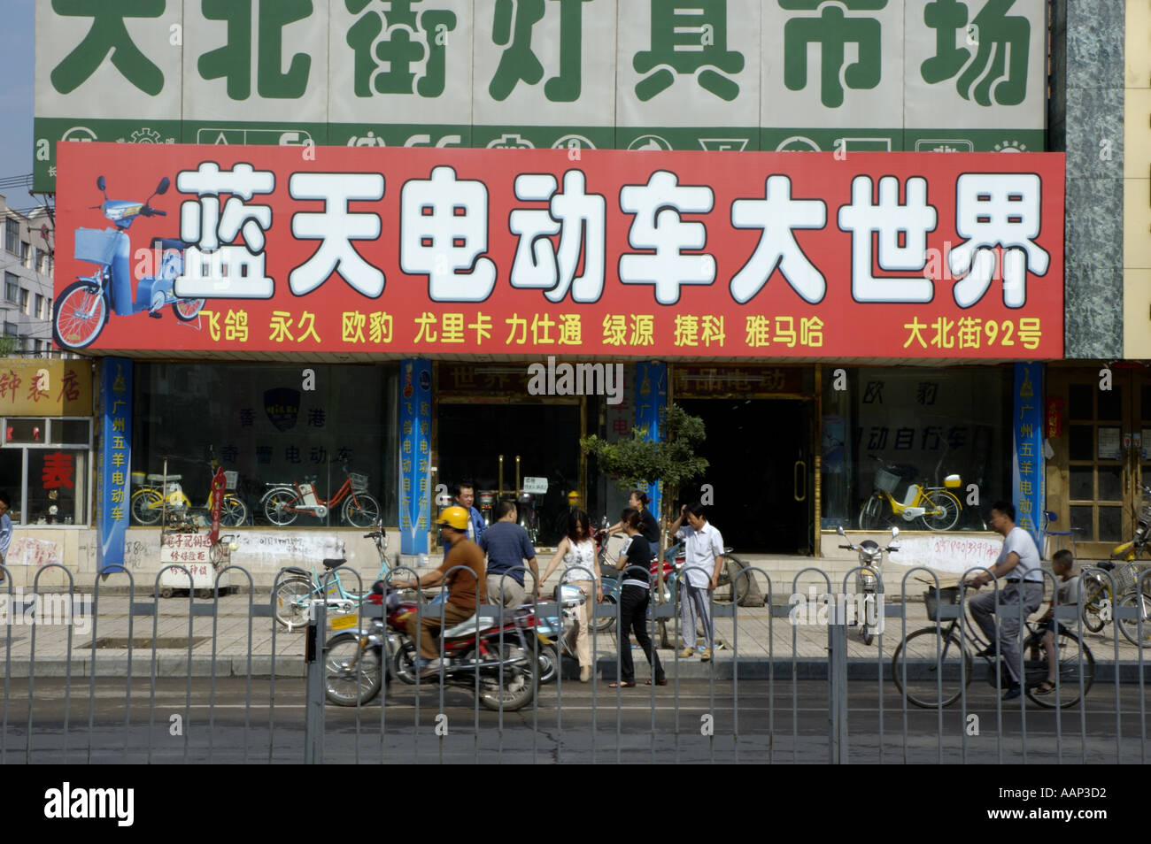 Datong, Provinz Shanxi, China - Roller und Fahrräder In A stark befahrenen Straße mit großen Werbetafeln hinter Stockfoto