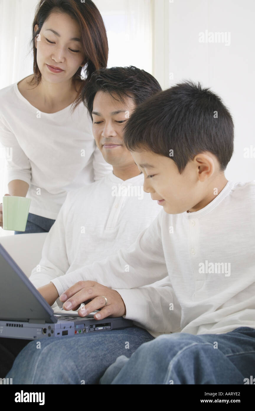 Vater, Sohn und Mutter suchen Computer mit Stockfoto