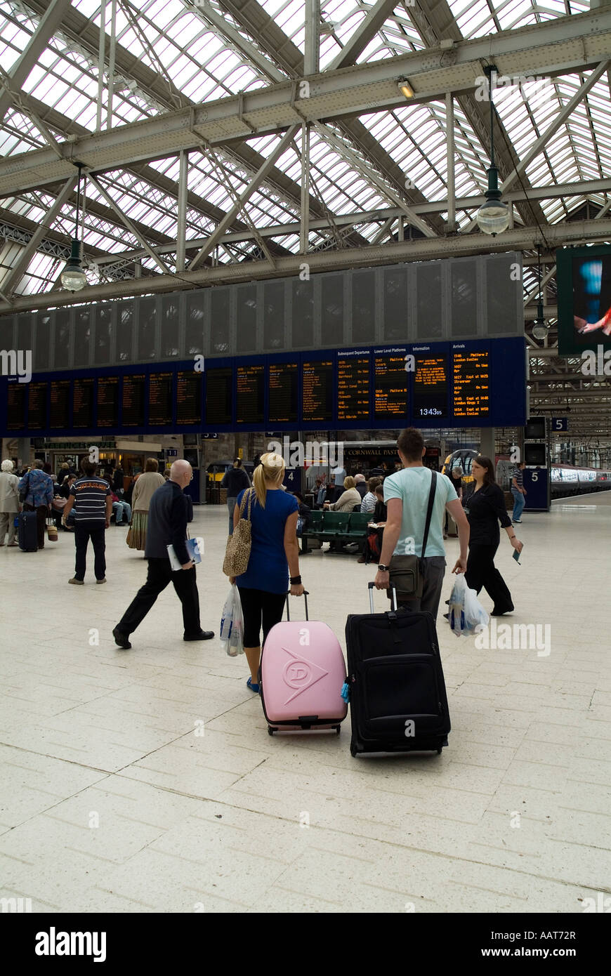 dh HAUPTBAHNHOF GLASGOW Passagierpaar mit Koffern Blick auf den Zugfahrplan an Bord zwei Reisende Reise scotland Rail Service Reise großbritannien Stockfoto