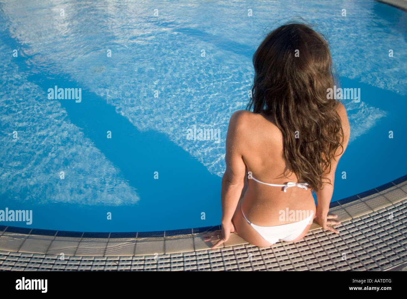 junge Frau sitzt am Rand des Swimming pool Stockfoto