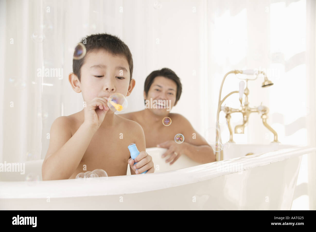 Vater und Sohn spielen mit Luftblasen im Badezimmer Stockfoto