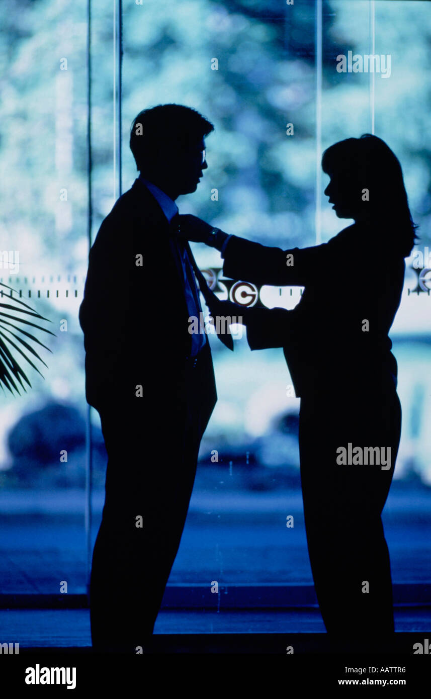 Silhouette Profil Frau Mannes Krawatte einstellen, während in der Lobby des modernen gläsernen Gebäude stehen. Stockfoto