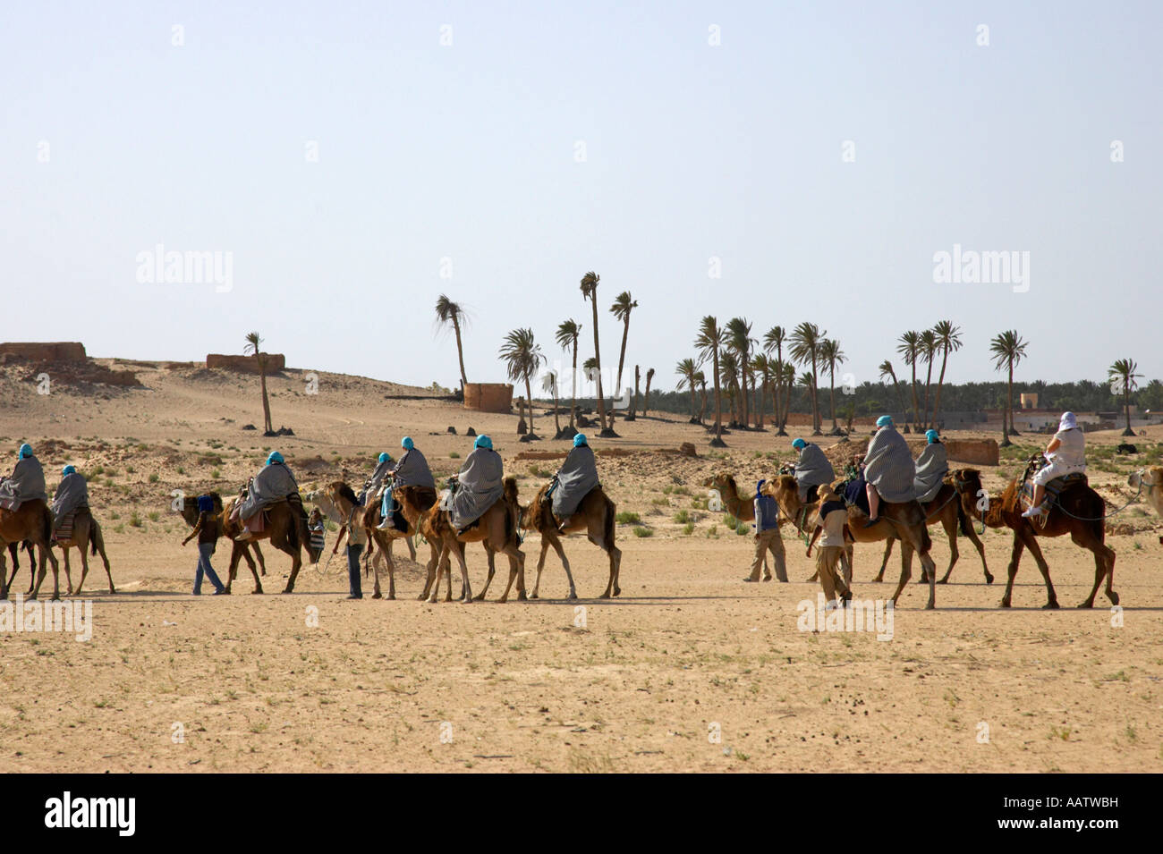 Gruppen von Touristen, vorbei an einer alten Oase und zerstörte Gebäude in die Sahara-Wüste in Douz Tunesien geführt Stockfoto
