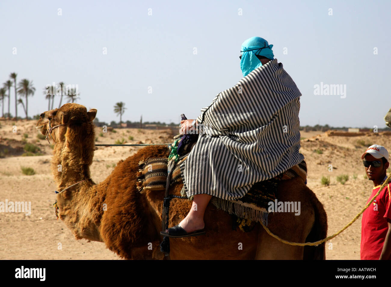 männliche Touristen in der Wüste Kleidung führte auf dem Rücken eines Kamels in die Sahara-Wüste in Douz Tunesien Stockfoto