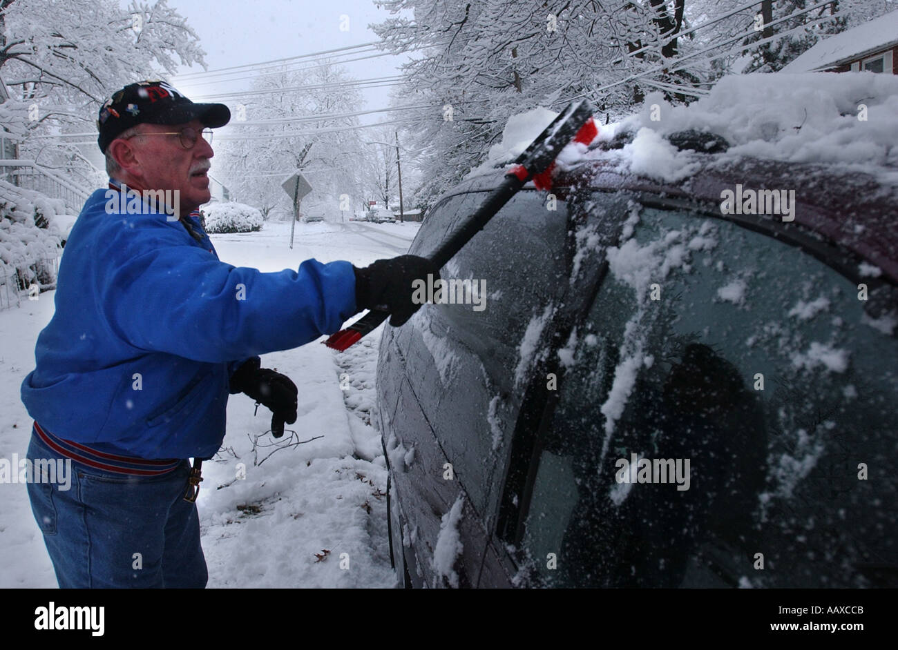 Mann, kratzen aus Schnee und Eis von einem Auto Automobil nach einem Schneesturm Stockfoto
