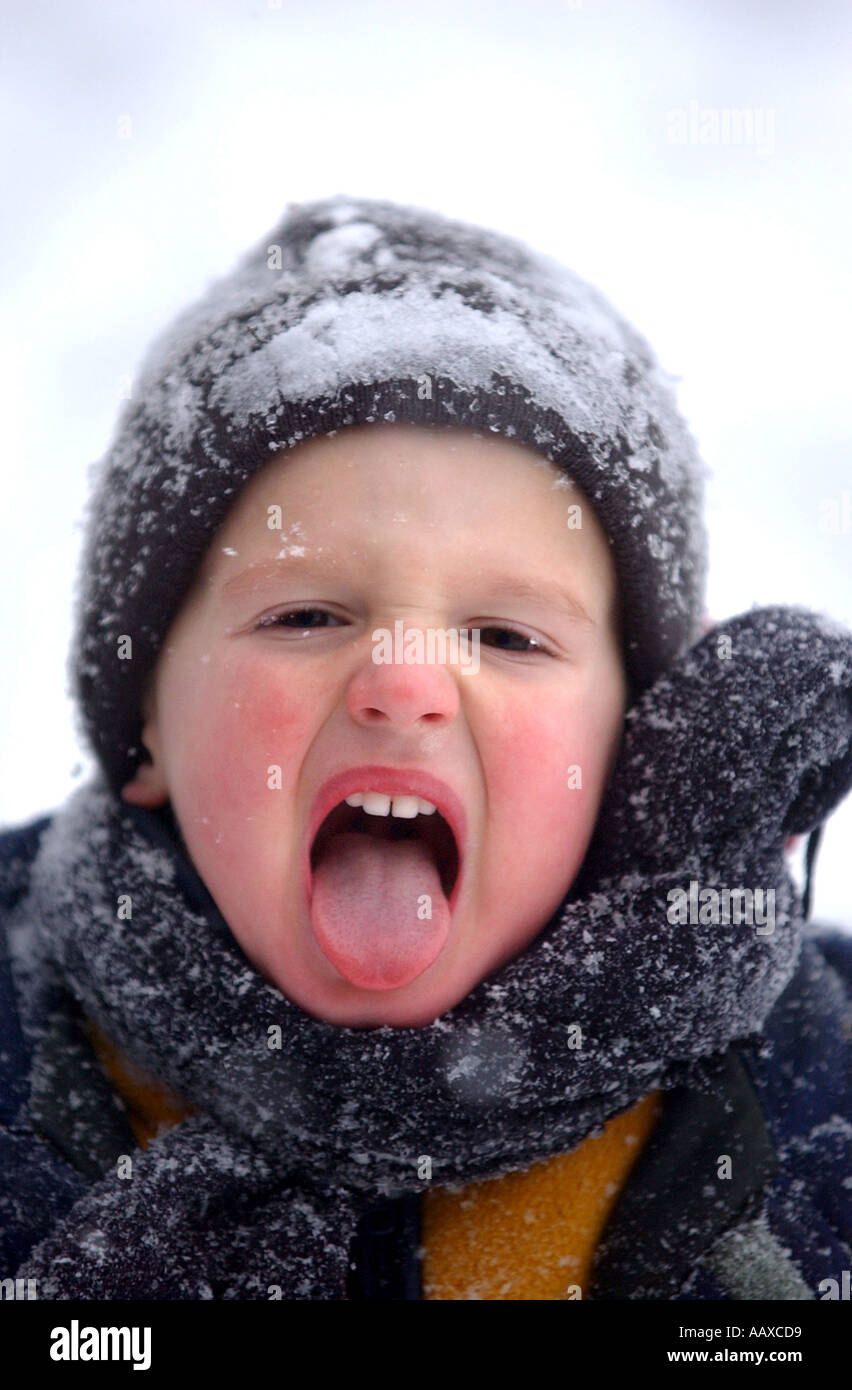 Kind junge Fang Schneeflocken auf der Zunge als Schnee fällt. "Winterwetter" "Kälte" Konzepte. Stockfoto