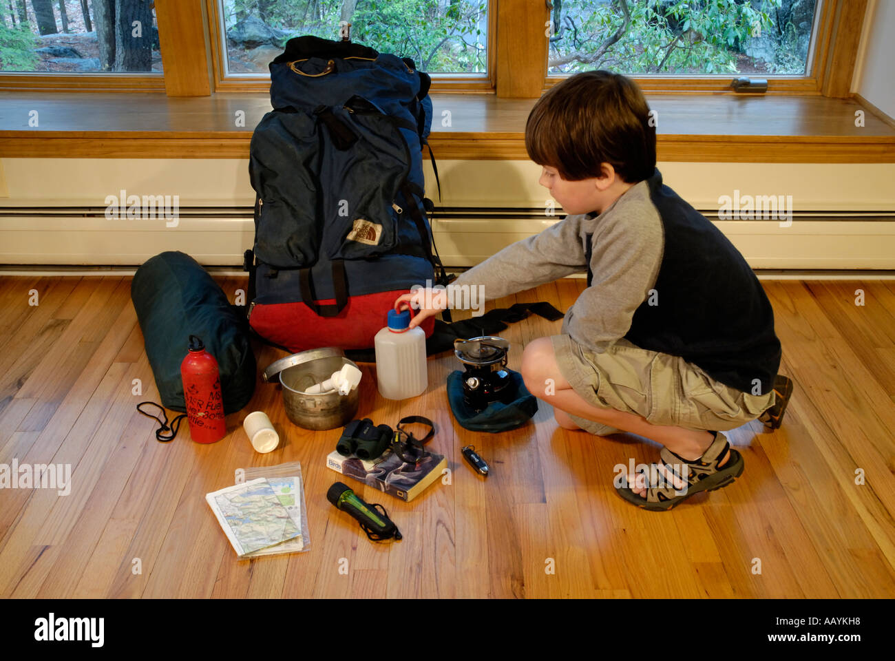 Junge für Wasserflasche zu erreichen, da er seine Campingausrüstung für einen Ausflug packt Stockfoto