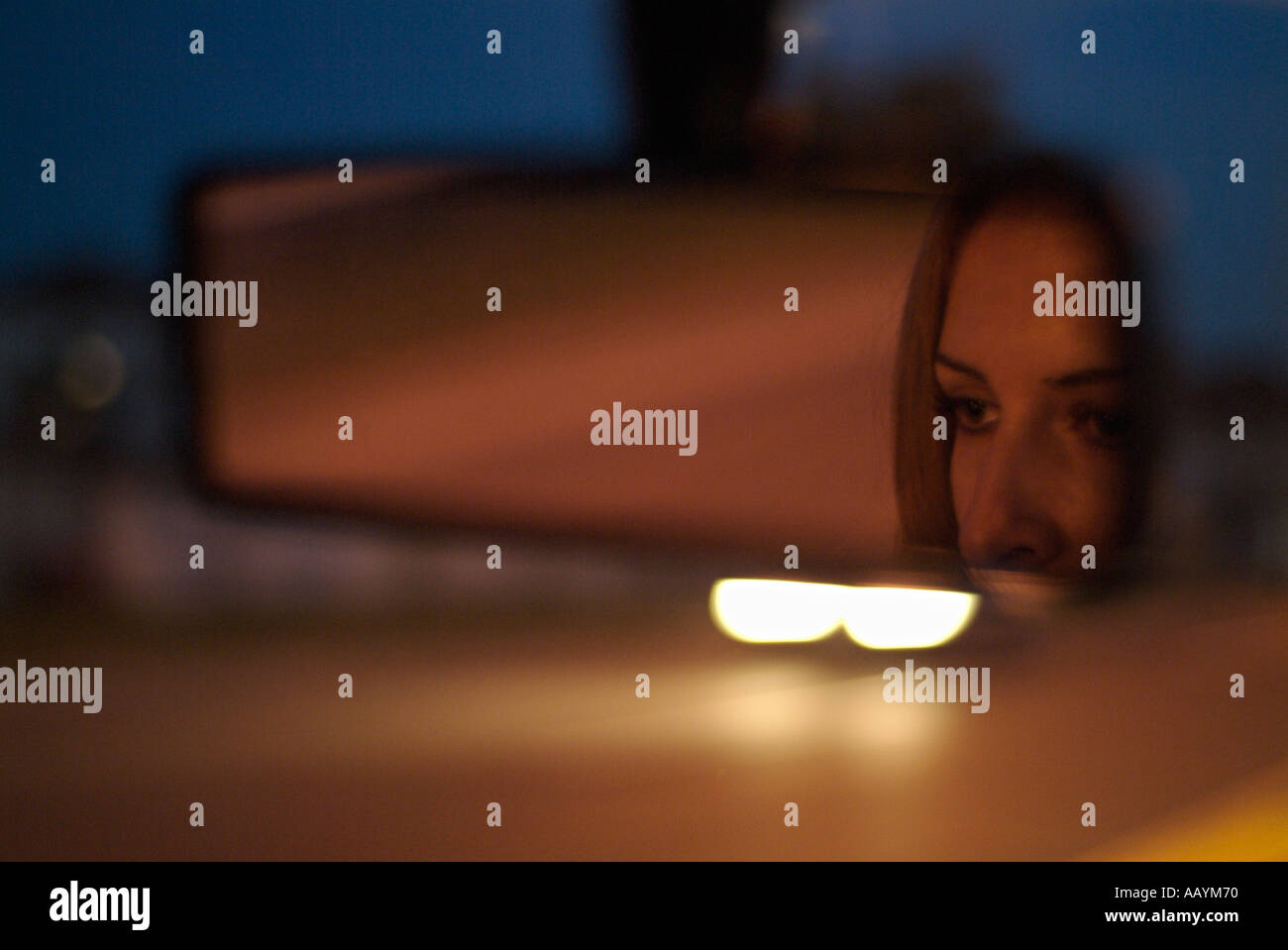 Rückspiegel mit Reflexion der ein Womans Gesicht in einem Auto fahren entlang einer Straße bei Nacht Stockfoto