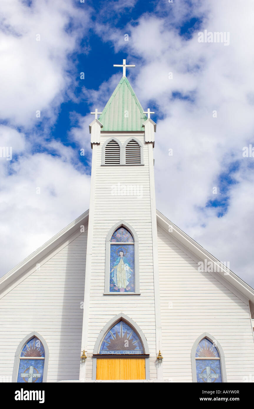 Kirche mit Kreuz und Glasmalerei vor blauem Himmel mit flauschigen weissen Wolken. Stockfoto