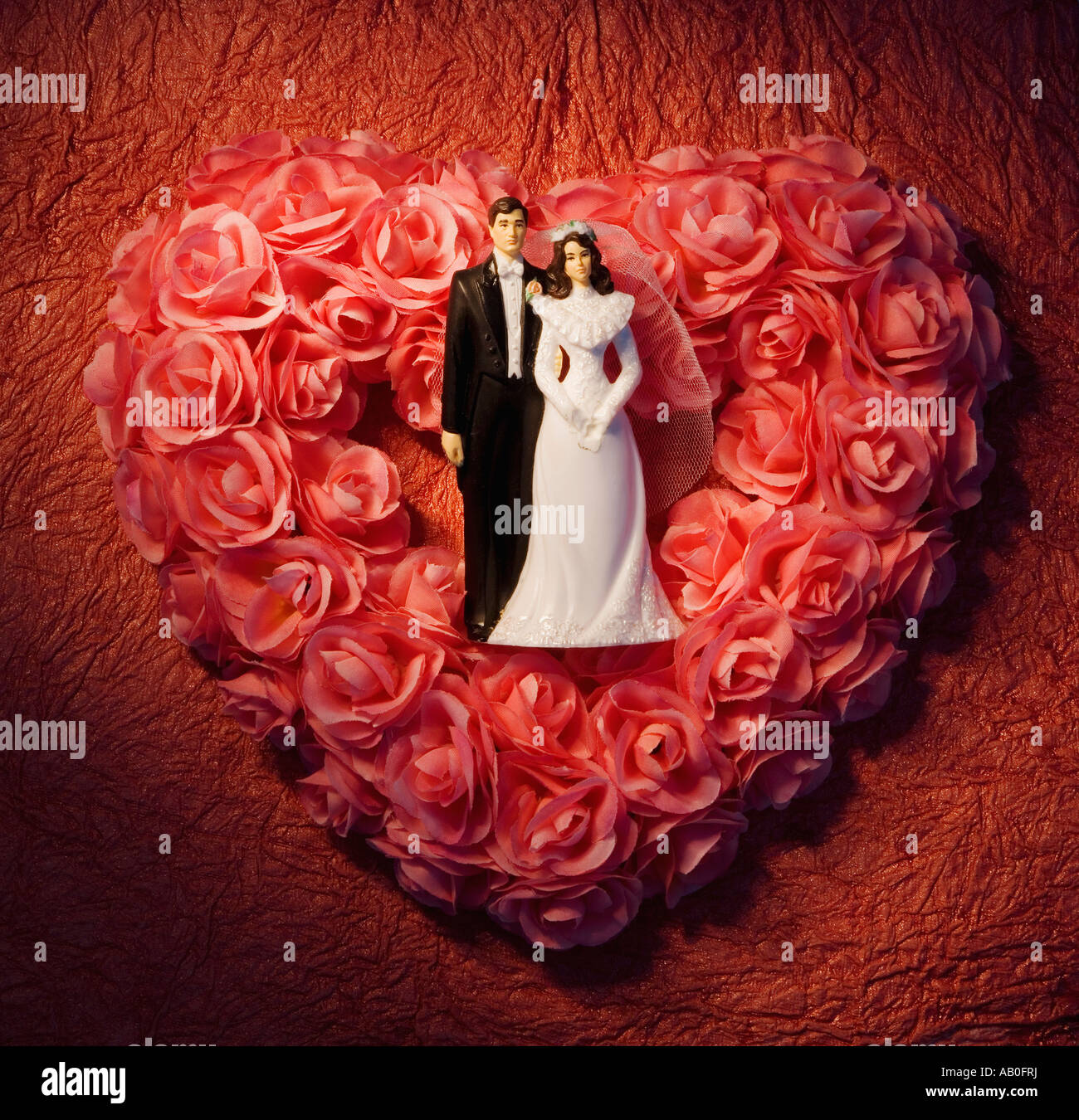 Herzförmige Blumenkranz mit Braut und Bräutigam Figuren Stockfoto