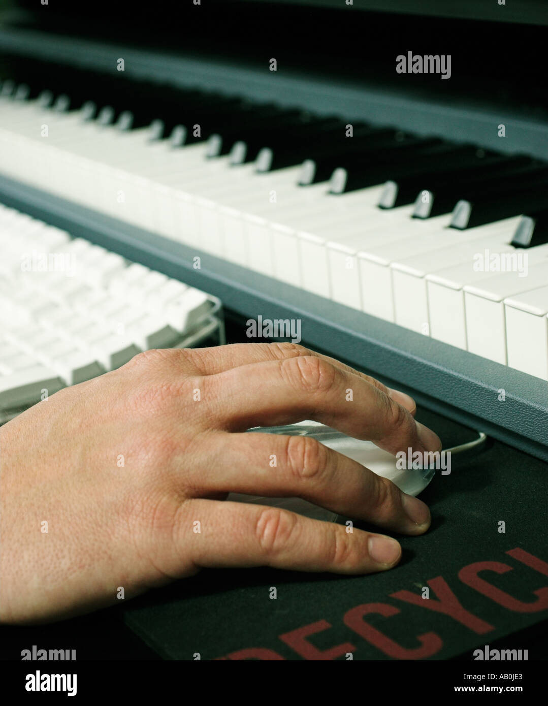 Nahaufnahme von Hand und Maus neben Computer und musikalische Tastatur Stockfoto