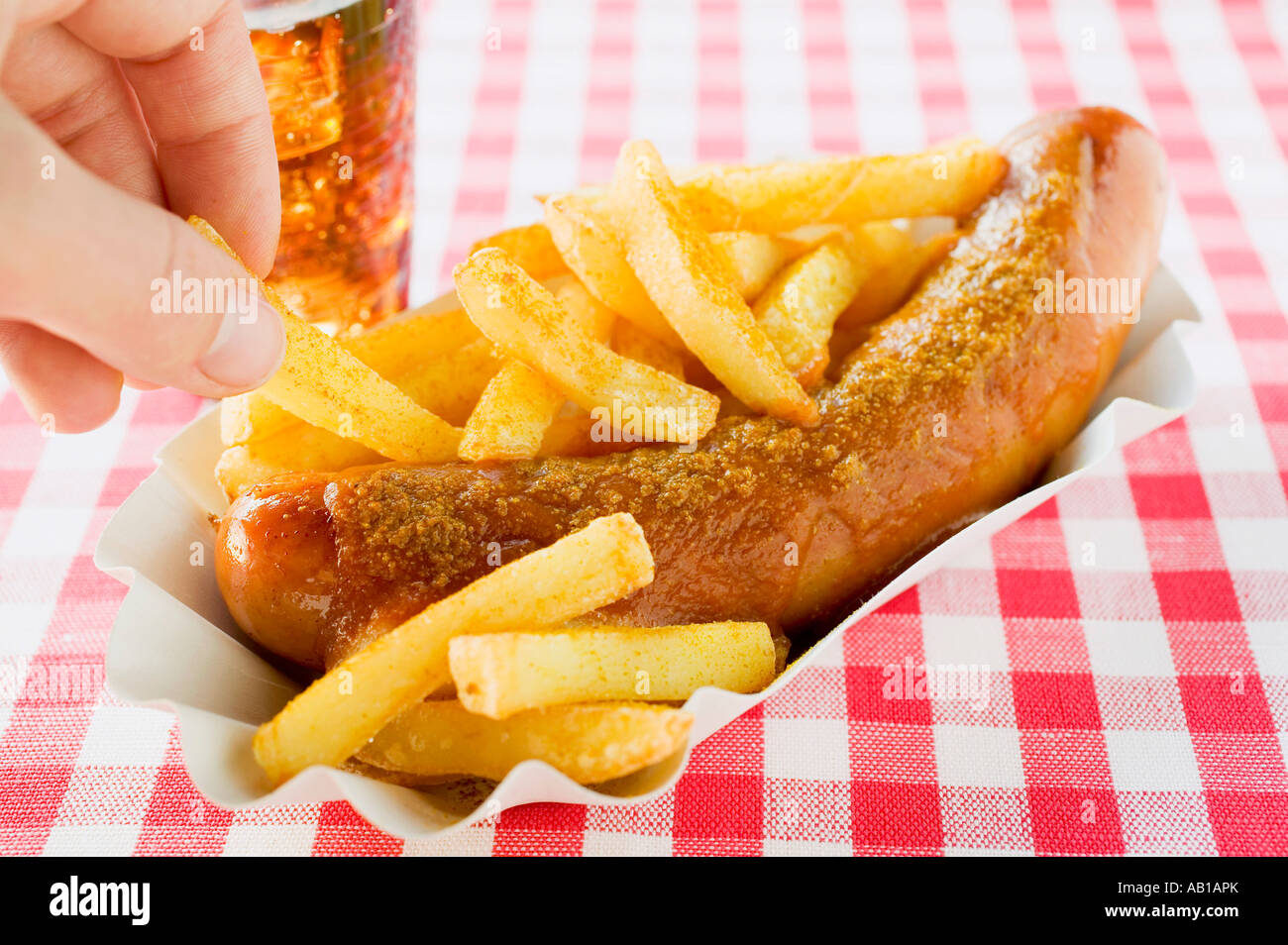 Hand nehmen Chip aus Papier Schüssel von Currywurst und Pommes FoodCollection Stockfoto