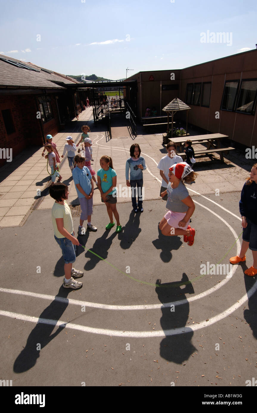 Leiter Gymraeg Aberystwyth walisische Sprache Grundschüler spielen, springen Seil Spiel bei Sonnenschein in der Pause Zeit Wales UK Stockfoto