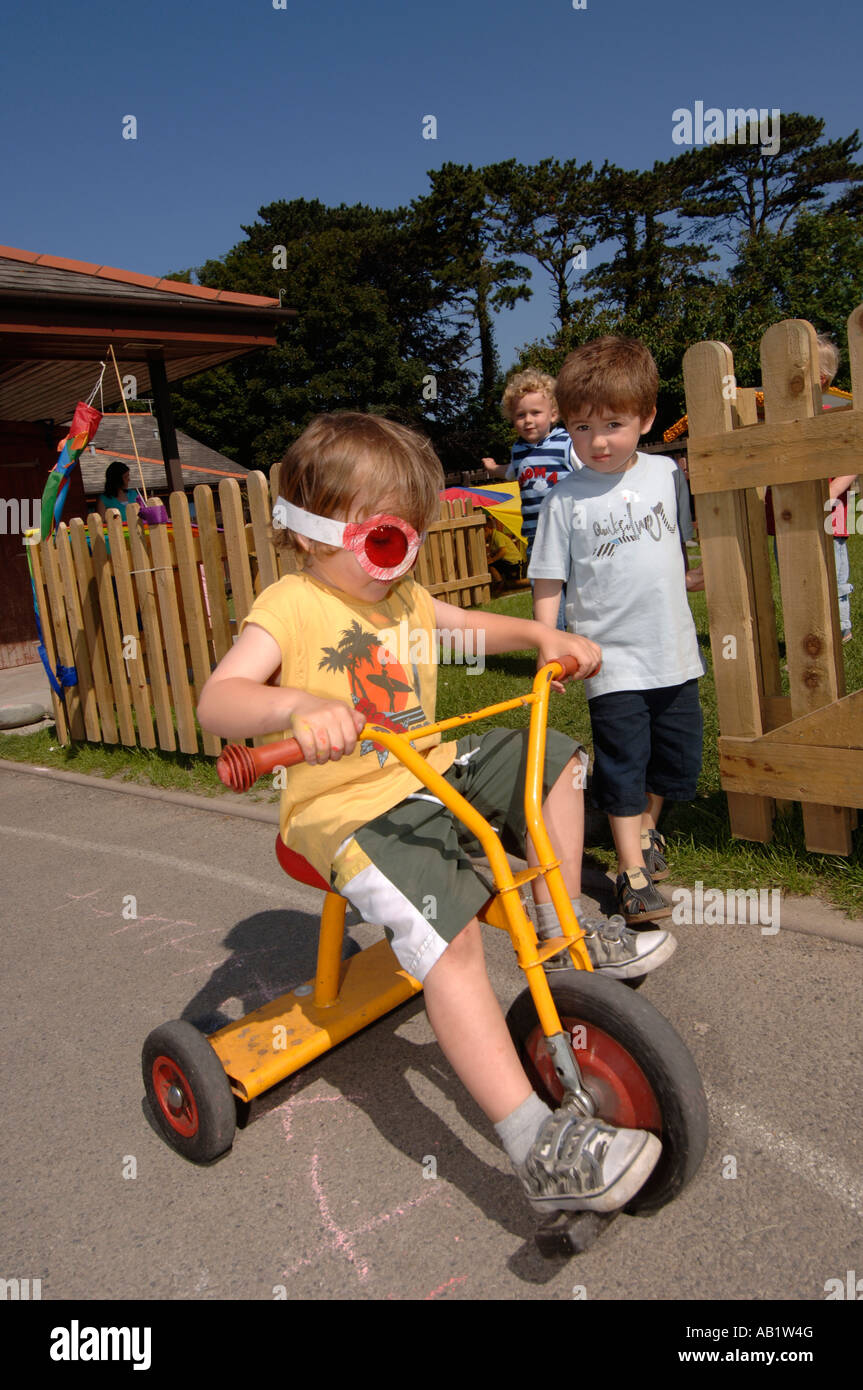 Leiter Gymraeg Aberystwyth walisische Sprache Grundschüler spielen im Freien in der Sonne auf Dreirad, Wales UK Stockfoto