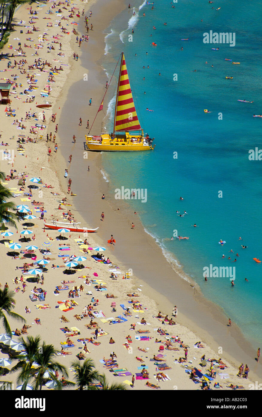 Blick auf Waikiki Beach Hawaii einen gelben Katamaran hat am Sonnenanbeter gefüllt Strand hochgezogen Stockfoto