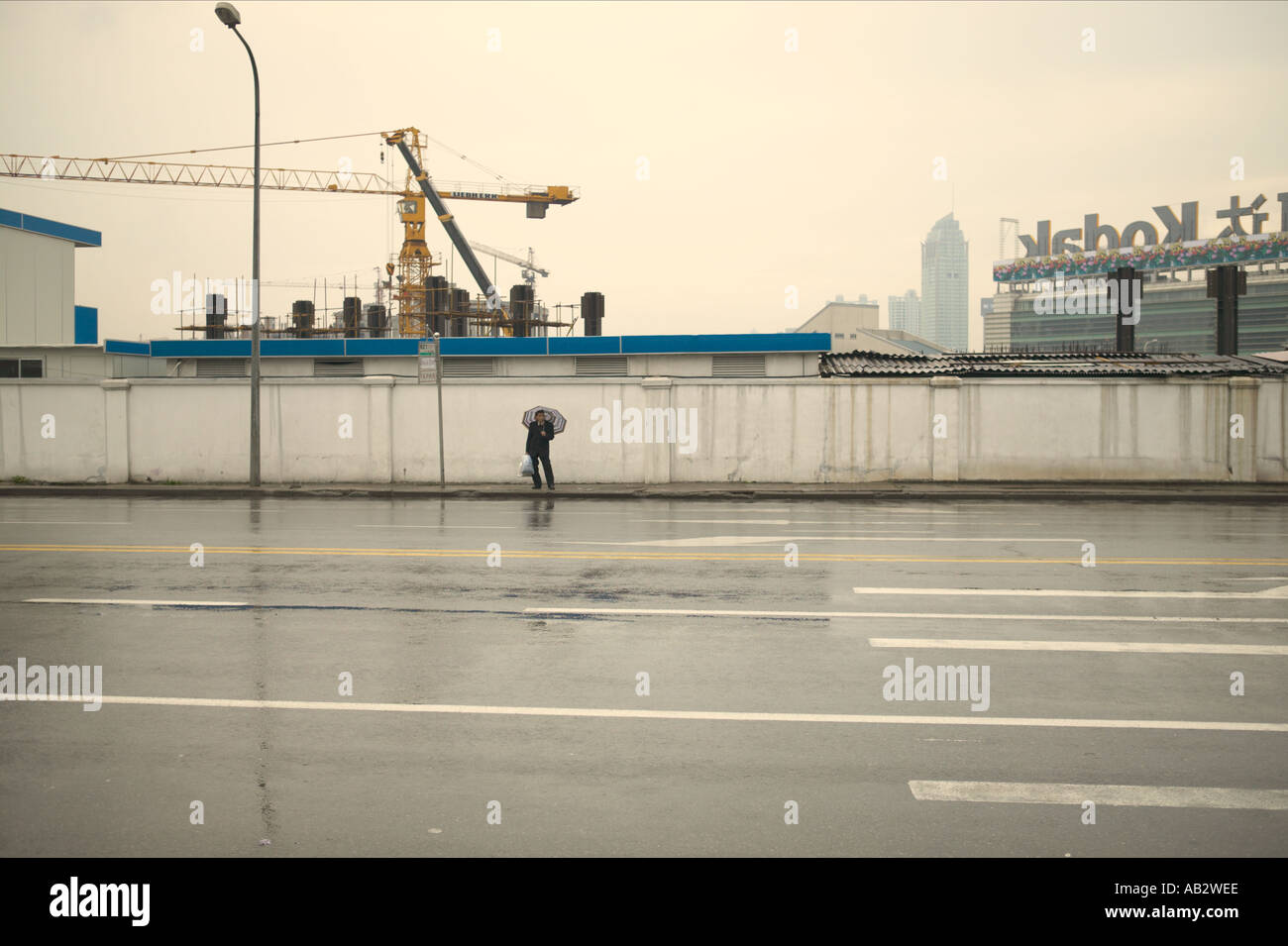 Ein Mann steht auf einem Pflaster im Regen halten einen Regenschirm in Shanghai Stockfoto