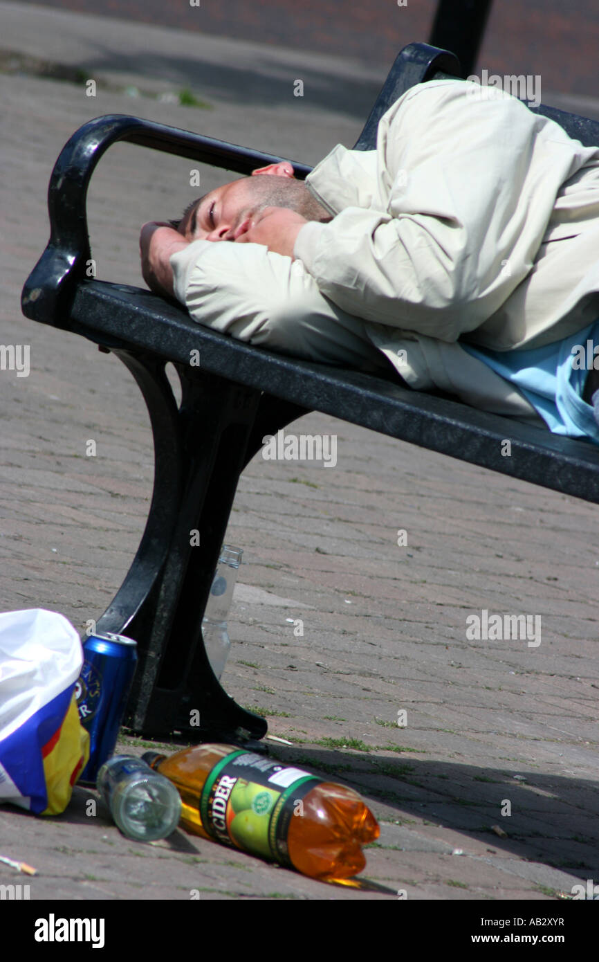 Junger Mann nach einer durchzechten Nacht, County Down, Nordirland auf Bank in der Straße in Downpatrick betrunken liegend Stockfoto