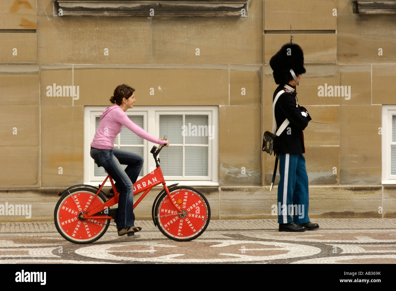 Ein Mädchen, kostenloser Verleih Fahrrad vorbei an einer königlichen Garde auf Amalienborg in Kopenhagen, Dänemark. Stockfoto