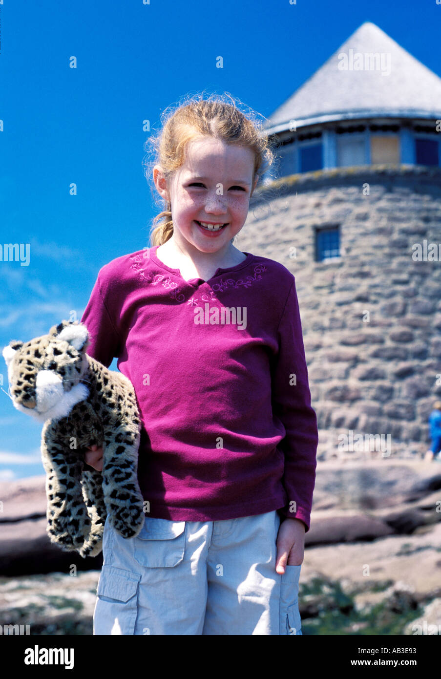 rote kurzhaarige Mädchen in den Urlaub mit Haustier Tiger Puppe auf des Ministers Insel New Brunswick Kanada mit Burg, wie Gebäude Stockfoto