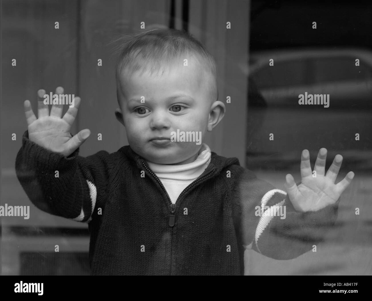 Kleiner Junge auf der Suche Glas Tür Stockfoto