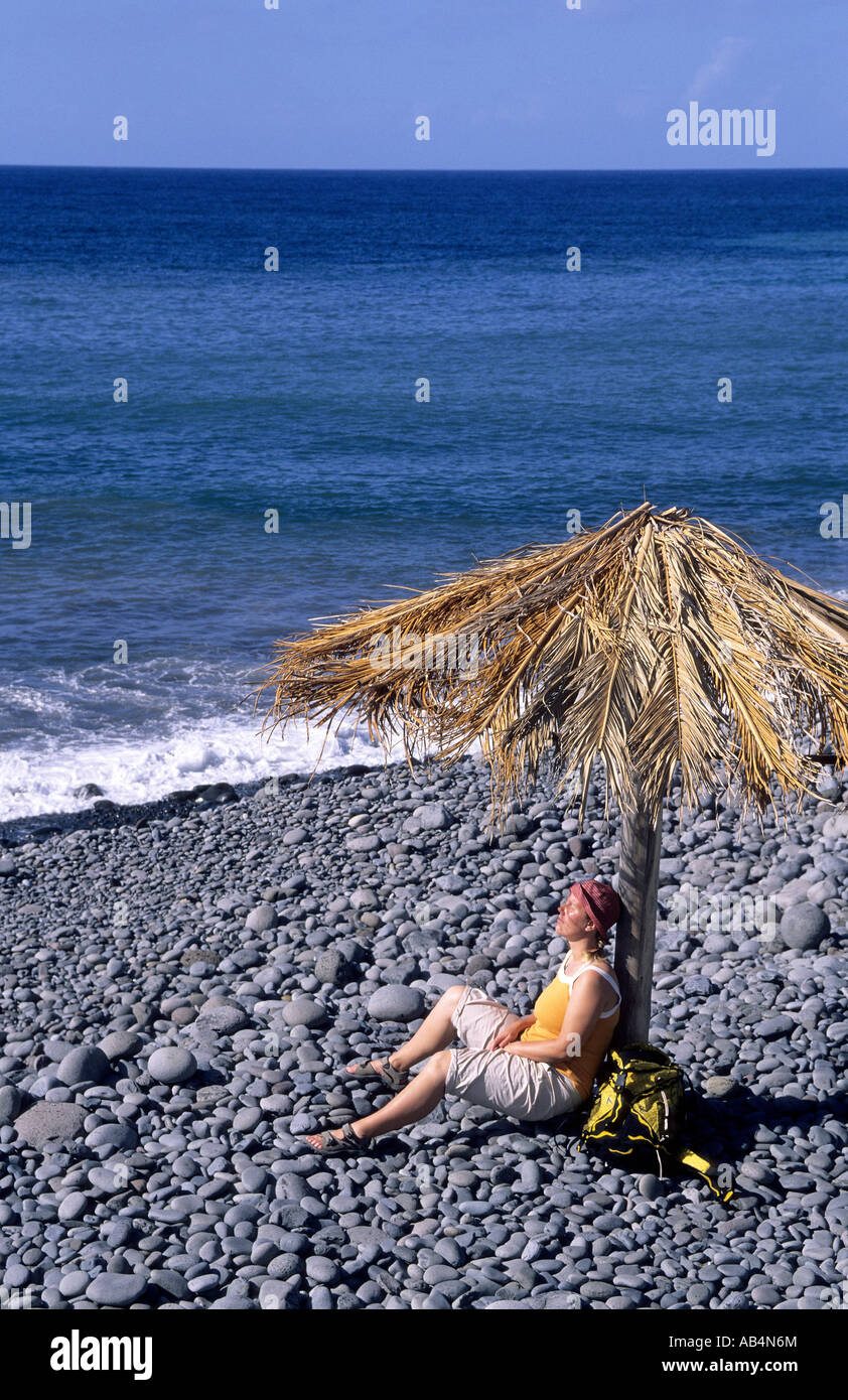 Frau sitzt unter Sonnenschirm Stockfoto