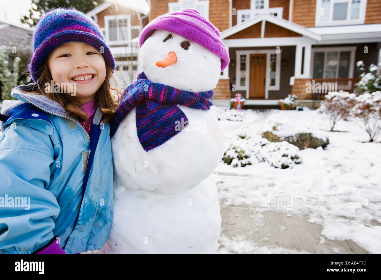 Porträt eines Mädchens mit Schneemann vor Hof Stockfoto
