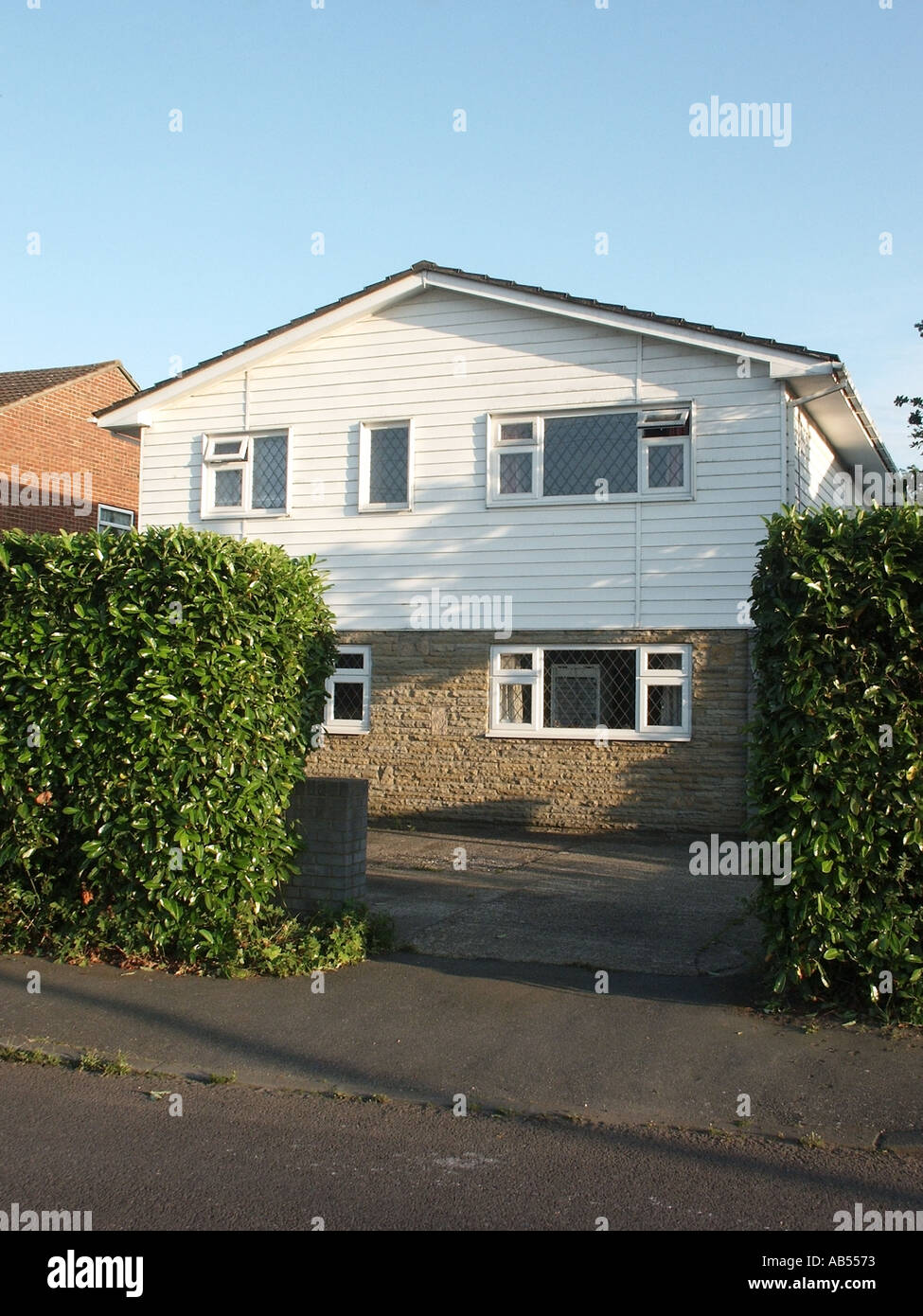 Essex freistehendes Haus mit Lorbeer-Front Hecke Auffahrt Stein untere Front Höhe UPVC Wetter Boarding über England UK Stockfoto