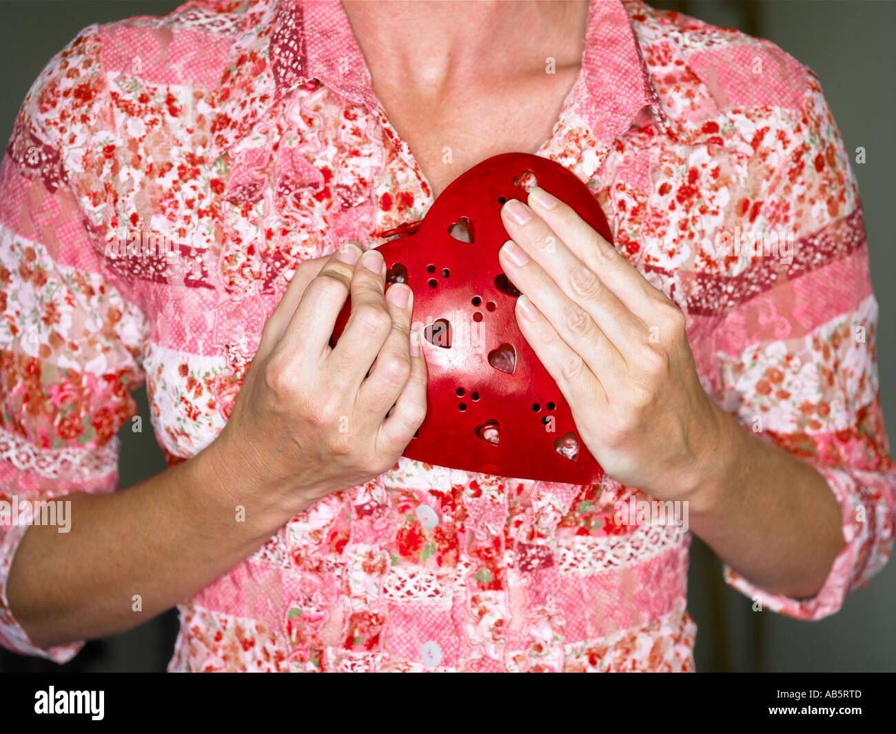 Frau mit einem roten Metallherz an ihre Brust Stockfoto