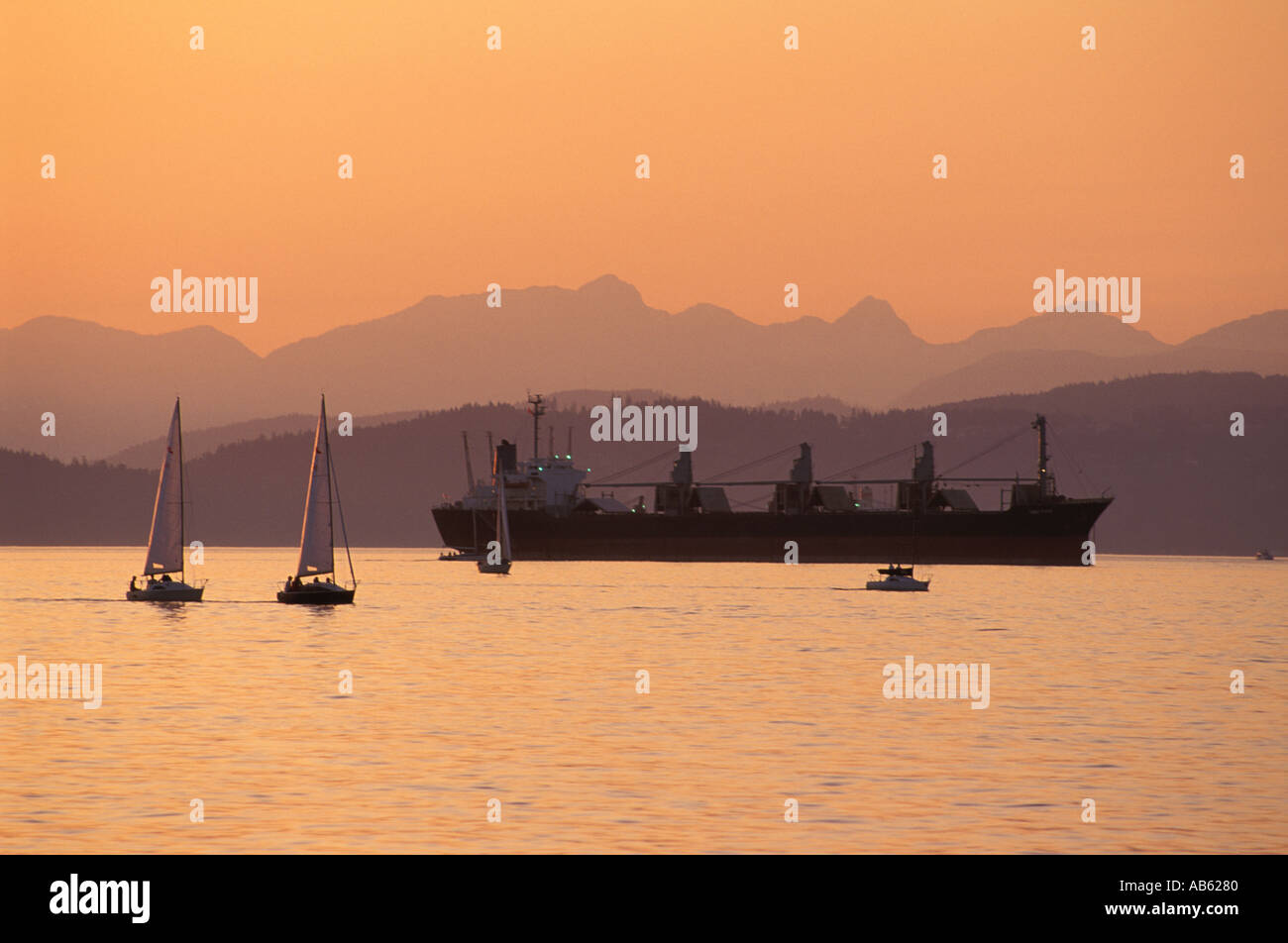 Segelboote und Tanker in English Bay mit West Vancouver und Howe Sound Bergen im Hintergrund Stockfoto