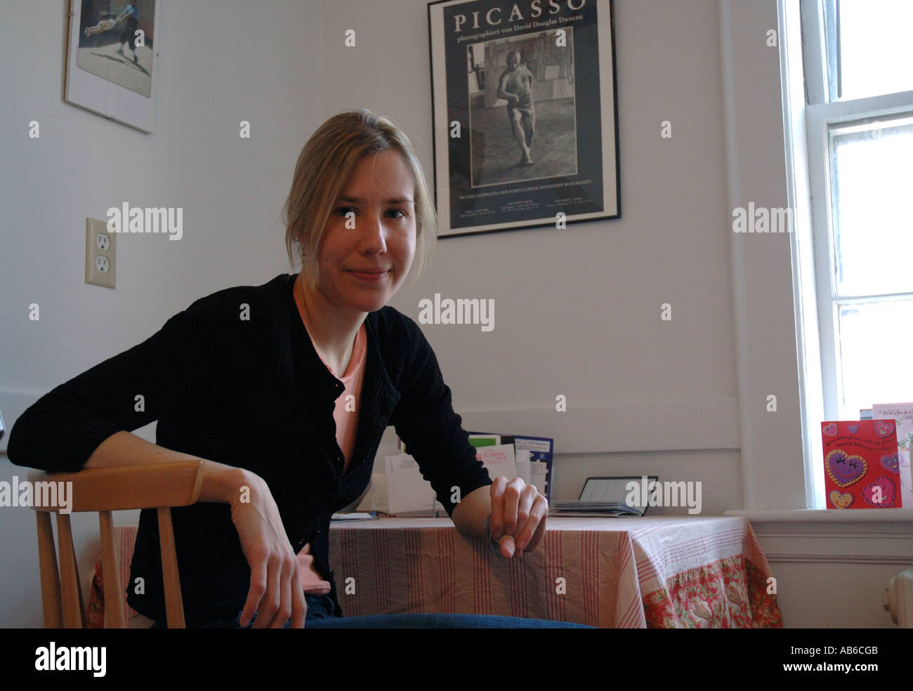 Porträt der jungen Frau in der Mitte der zwanziger Jahre sitzen am Küchentisch in ihrer Wohnung. Stockfoto