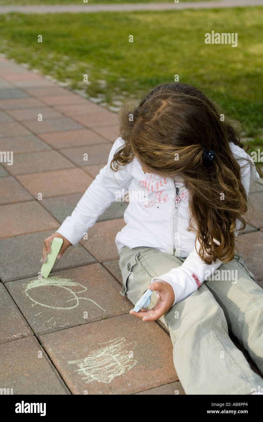 Kleines Mädchen alleine zu spielen, mit Kreide zeichnen von Gesichtern Stockfoto