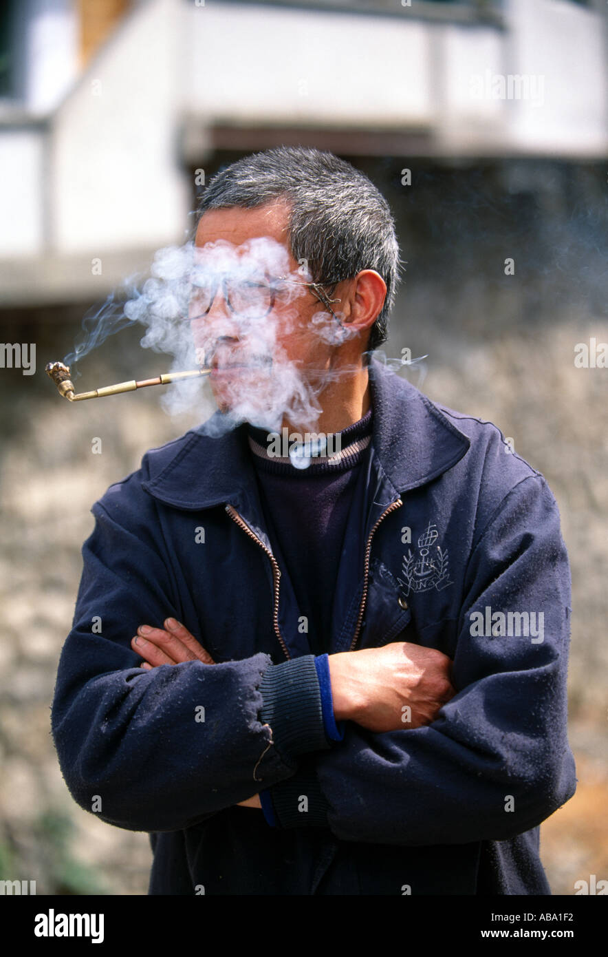 Mann rauchen Pfeife Gesicht verloren in Rauchwolke am Markt in kleinen ländlichen Dorf in der Nähe von Wuxi China Asien 042503 Stockfoto