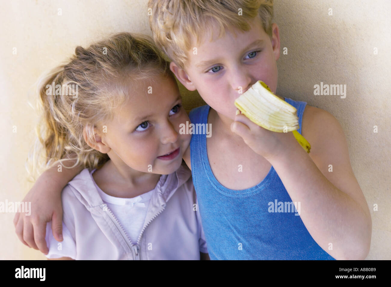 Junge Schwester umarmt und Banane essen Stockfoto