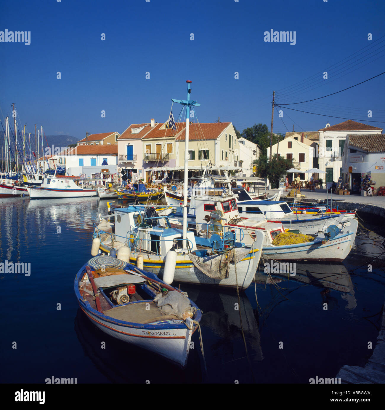 Angelboote/Fischerboote vertäut im Hafen mit Cafés, Geschäften und Häusern am Kai Fiscardo Kephallonia Insel griechische Inseln Griechenland Stockfoto