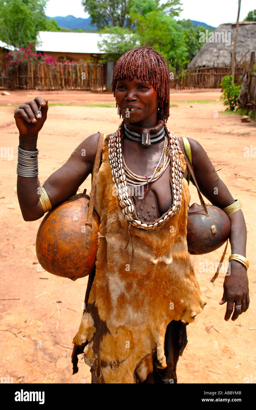 Frau aus dem Volk der Hamar trägt ein Ledertuch und typischen Ton Frisur ein Metall und Kauri Muschel Kette und Kalabasses bei der Stockfoto