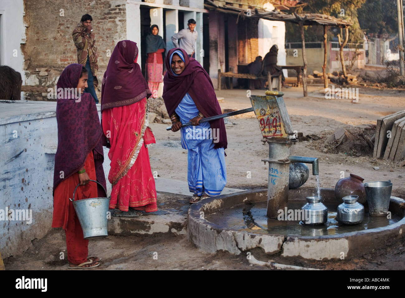 Frauen mit bunten Sari sammeln Wasser mit einer Pumpe gut Jaipur Rajasthan Indien Stockfoto