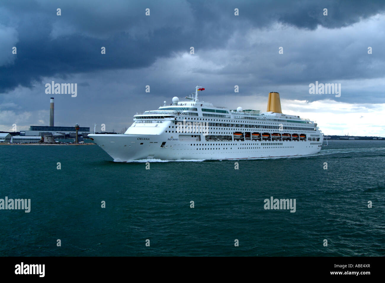 Die Oriana Kreuzfahrtschiff weitergibt Southampton Wasser England UK dramatische bedecktem Himmel Fawley Kraftwerk. Stockfoto
