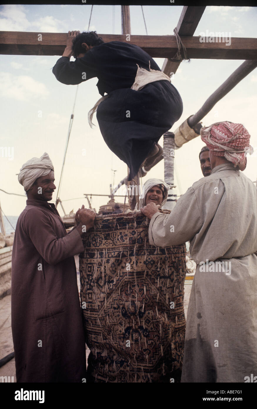 Eine arabische Dhau Segel sind nach unten und furled. Manpower und scherzen bekommen sie in einer Tasche Stockfoto