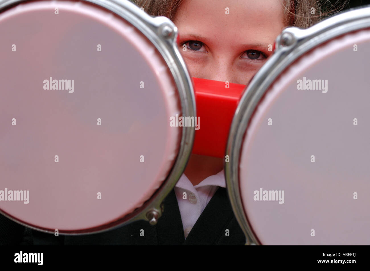 Ein junges Mädchen auf der Suche durch den Spalt des Bongo-Trommeln. Stockfoto