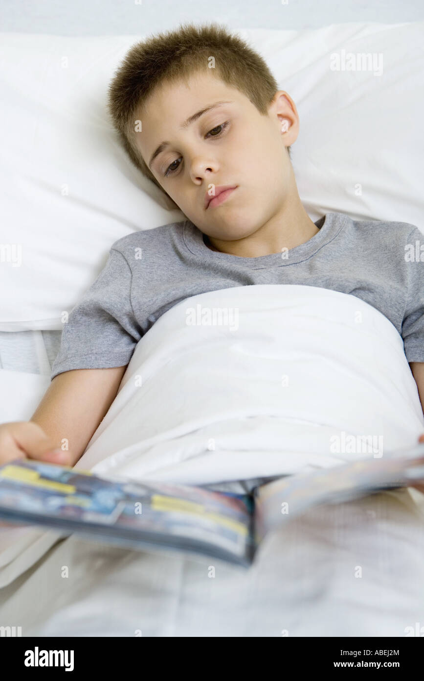 Kranken jungen liegen im Bett und Las Comic-Buch Stockfoto