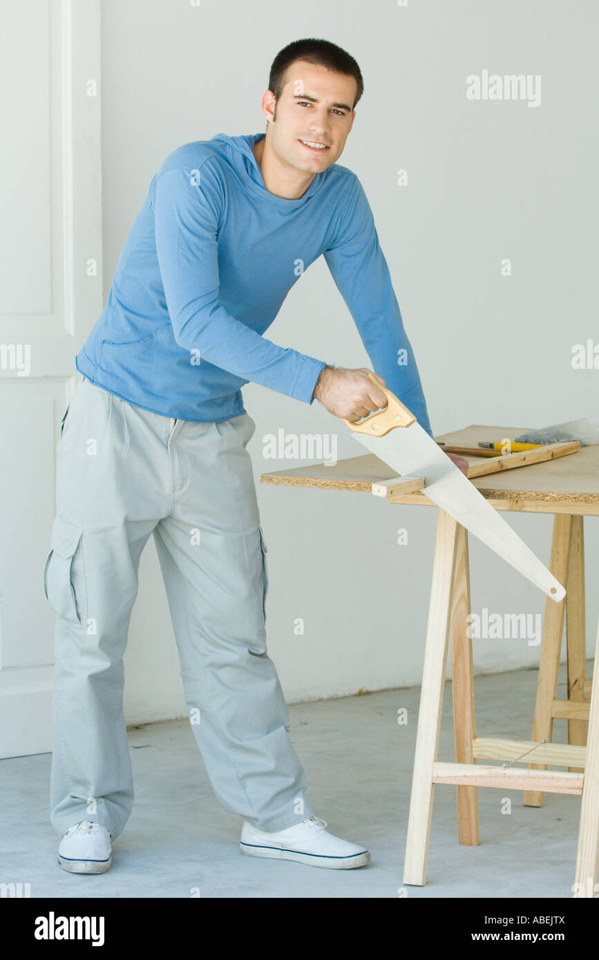 Mann Sägen Stück Holz, Blick in die Kamera Stockfoto