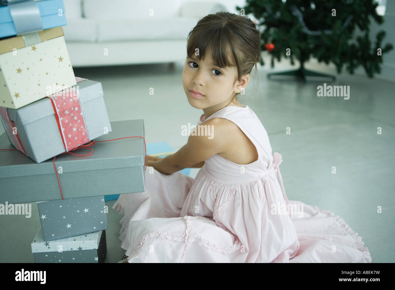 Mädchen sitzen neben Stapel Geschenke Stockfoto