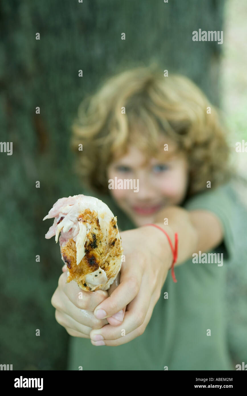 Junge hält sich gegrillte Hähnchenschenkel Stockfoto