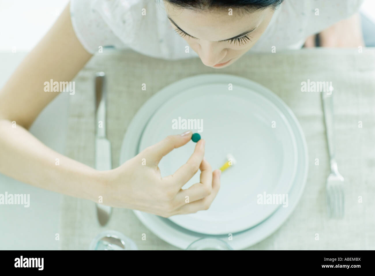 Frau sitzt am leeren Teller mit vitamin Stockfoto