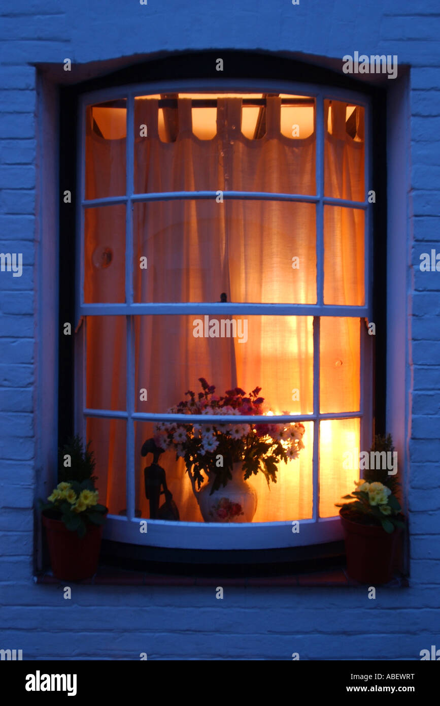 Warme Licht aus dem Wohnzimmer-Fenster in der Abenddämmerung Stockfoto