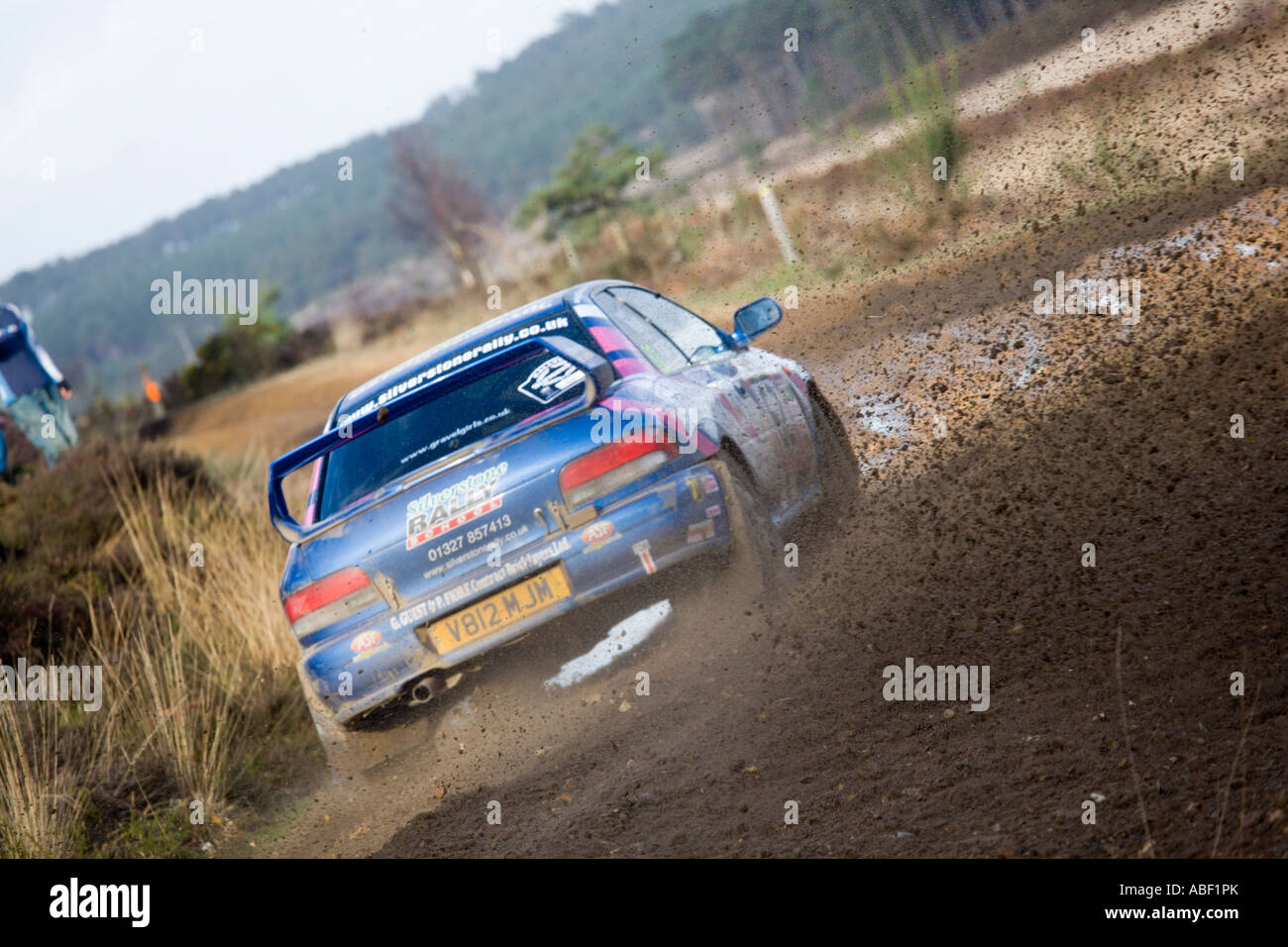 Blauen Subaru Impreza-Rallye-Auto fahren Aktion Spritzwasser durch Pfütze Spritzen Kies Steinen, Schmutz und Schlamm, wie sich herausstellt eine Ecke Stockfoto