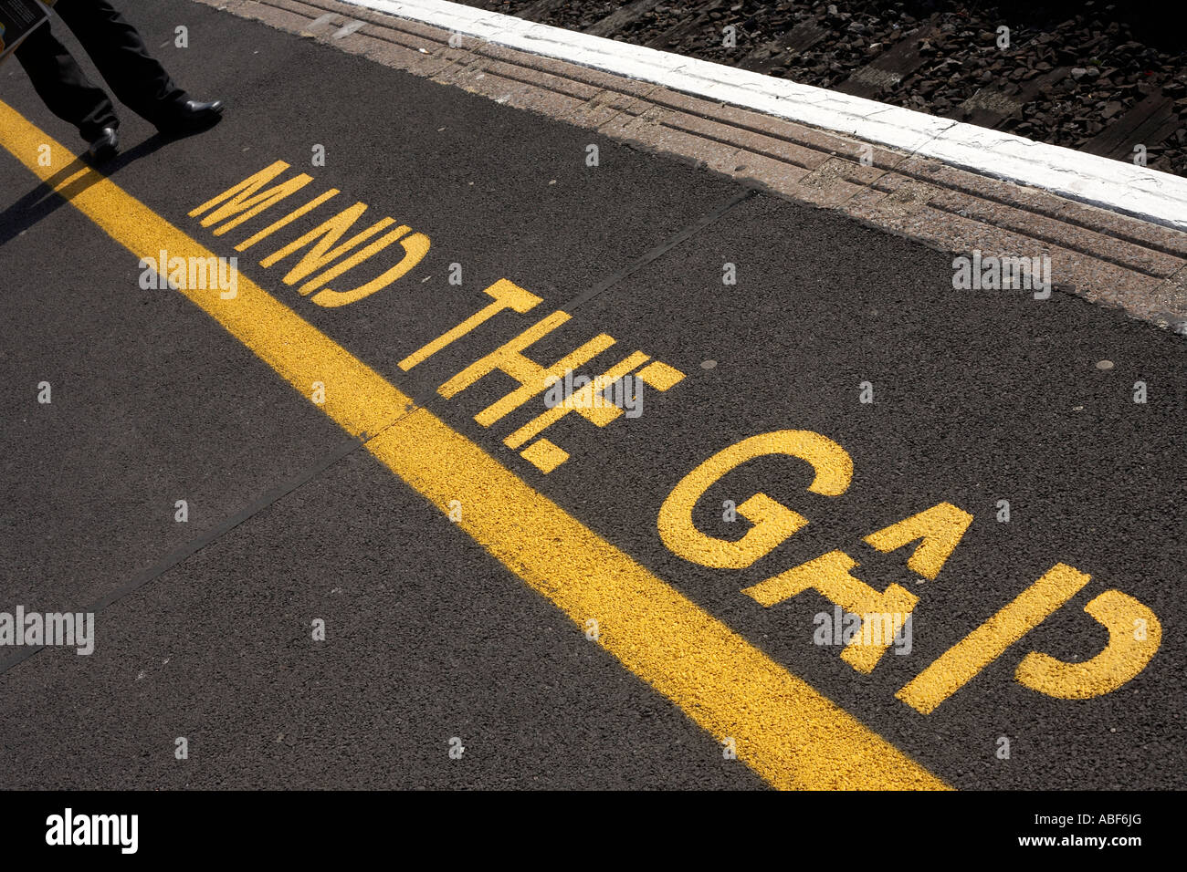 Die Worte Mind The Gap sind am Rande des neu angelegten Asphalt auf Plattformen an einer Station England Schablonen. Stockfoto